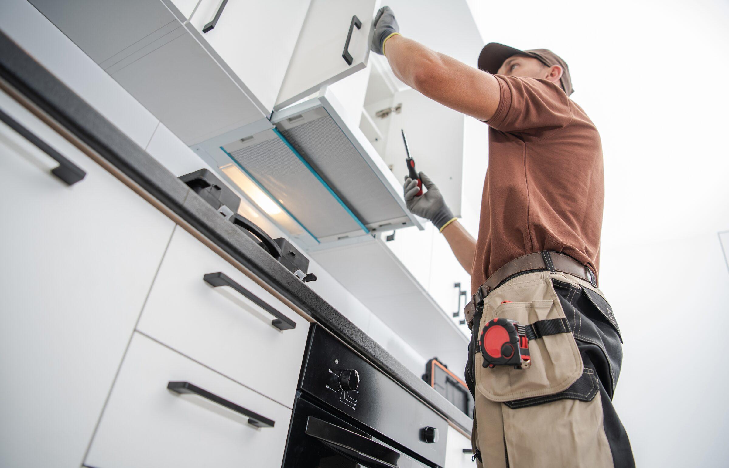 Installer fitting a white upper cabinet above a built-in oven